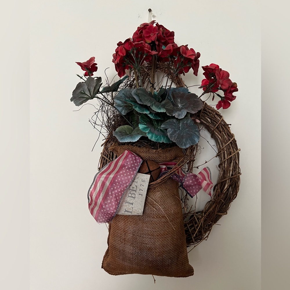 Hand crafted Round Grapevine Wreath with burlap bag of geranium flowers.